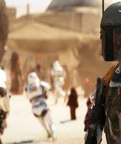 Star Wars Battlefront 2 screenshot of Boba Fett standing in Mos Eisley while Stormtroopers charge down the streets.